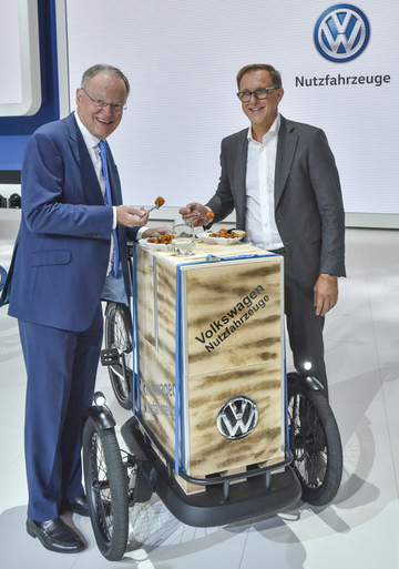 IAA Hannover: Stephan Weil und Thomas Sedran (Vorstandsvorsitzender VW Nutzfahrzeuge) mit Currywurst und Cargo-e-Bike