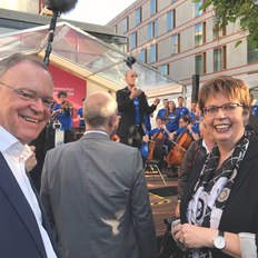 Ministerpräsident Stephan Weil und Europaministerin Birgit Honé auf dem Sommerfest in der Landesvertretung in Berlin. Im Hintergrund speilt das Niedersächsische Jugendsinfonieorchester.