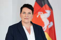 Portraitaufnahme von Ministerin Melanie Walter vor einer Niedersachsenflagge.