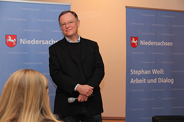 Blick aus dem Zuschauerraum Richtung Ministerpräsident, der mit dem Mikrofon in der Hand den Ausführungen eines Bürgers lauscht.