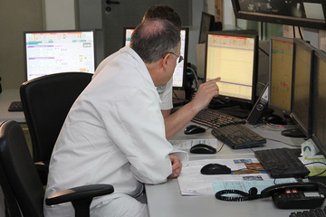 Ministerpräsident Weil am Schreibtisch vor mehreren Monitoren; ein Mitarbeiter von SAPPI gibt Erläuterungen