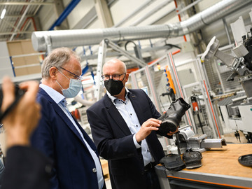 Besuch der Desma Schuhmaschinen GmbH in Achim; Stephan Weil betrachtet die Produktionsmaschine