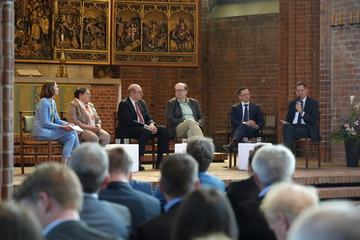 Ministerpräsident Olaf Lies spricht auf einem Podium in der Marktkirche Hannover, neben ihm sitzen Wissenschaftsminister Falko Mohrs, Energieminister Christian Meyer, Europa- und Regionalministerin Melanie Walter.