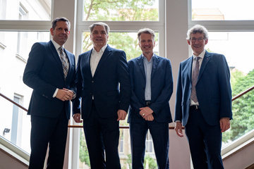 Ministerpräsident Olaf Lies steht mit dem Chef der Staatskanzlei und Vertretern des Niedersächsischen Städtetages auf der Treppe der Niedersächsischen Staatskanzlei vor einer Fensterfront.