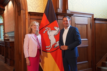 Bundesbildungsministerin Karin Prien steht mit dem Niedersächsischen Ministerpräsidenten Olaf Lies vor der Niedersachsenflagge
