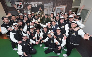 Ministerpräsident Olaf Lies steht mit einer großen Männergruppe, die alle die gleichen Jacken tragen vor der Fotowand