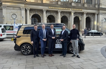 Ministerpräsident Lies steht mit drei weiteren Männern vor einem gold-schwarzen ID Buzz