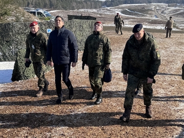 Ministerpräsident Olaf Lies geht in einer Reihe mit drei Soldaten. Drei Personen schauen nach oben.