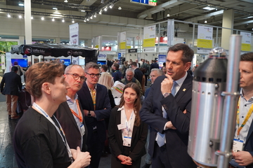 Ministerpräsident Olaf Lies steht an einem Stand auf der Hannover Messe und lässt sich etwas erklären, um ihn herum stehen einige Menschen