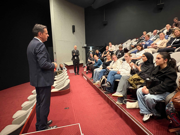 In einem Hörsaal mit roten Sitzreihen spricht Ministerpräsident Olaf Lies vor einer Gruppe von Jugendlichen und Erwachsenen. Mehrere Schülerinnen sitzen in den vorderen Reihen und beteiligen sich am Gespräch.