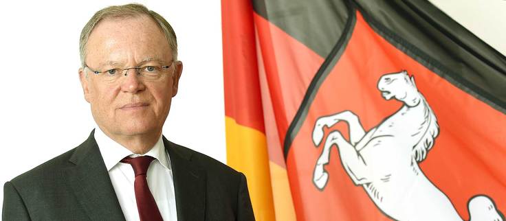 Ministerpräsident Stephan Weil steht vor dem Niedersachsenwappen.