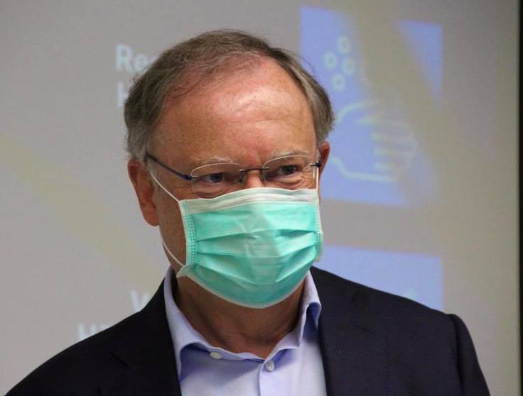 Ministerpräsident Stephan Weil mit Mund-Nasen-Bedeckung vor einem Hinweisschild, das Ratschläge zur Handhygiene gibt.
