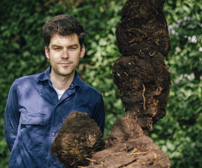 Philipp Modersohn steht hinter seiner Lehm-Skulptur "Die Erschöpften" im Garten der Landesvertretung Niedersachsen in Berlin.