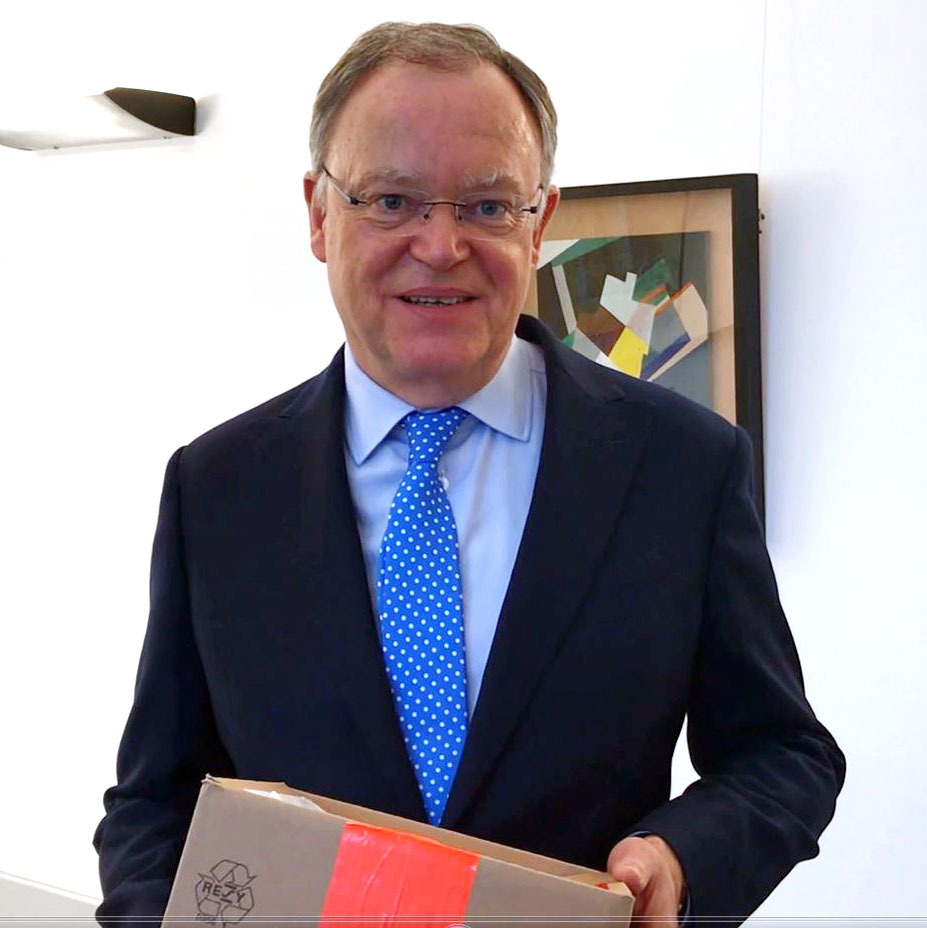 Ministerpräsident Stephan Weil mit einem Paket in den Händen.