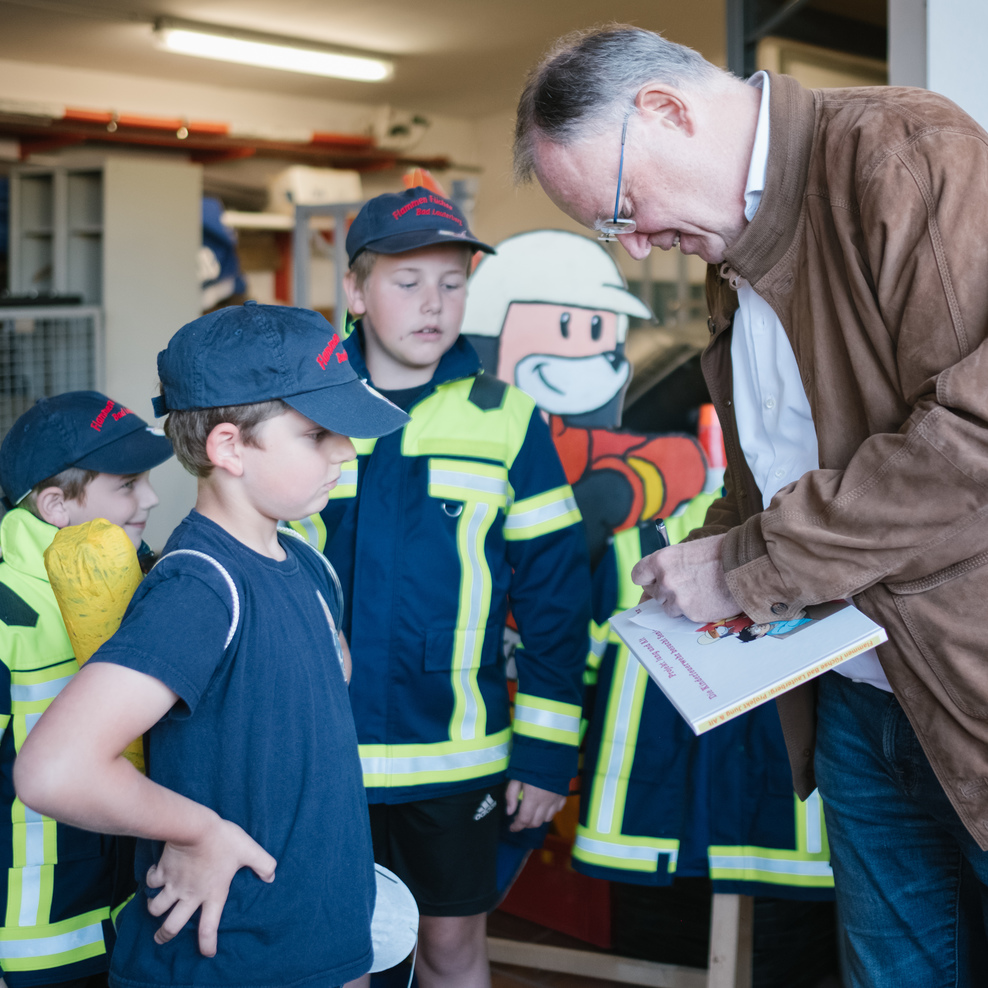 Ministerpräsident Stephan Weil gibt Kindern der Kinderfeuerwehr Bad Lauterberg Autogramme.