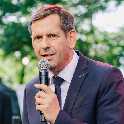 Ministerpräsident steht mit Mikrofon auf einer Bühne und spricht zum Publikum des Sommerfestes der Niedersächsischen Landesregierung. Neben ihm steht Veronika Dicke, Beauftragte der Landesregierung beim Bund.